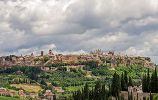 View of the Umbrian town, Orvieto, set atop a tufo rock with rolling green hills in the foreground.